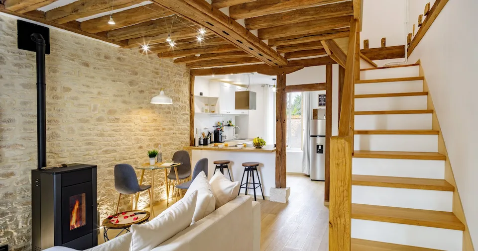 Intérieur rénové avec murs en pierre, poutres en bois et escalier