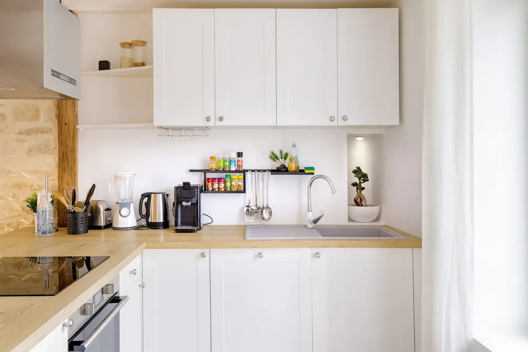 Cuisine blanche rénovée avec mur en pierre et plan de travail en bois