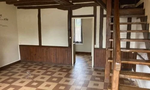 Pièce ancienne avec poutres, boiseries et sol à motifs avant travaux